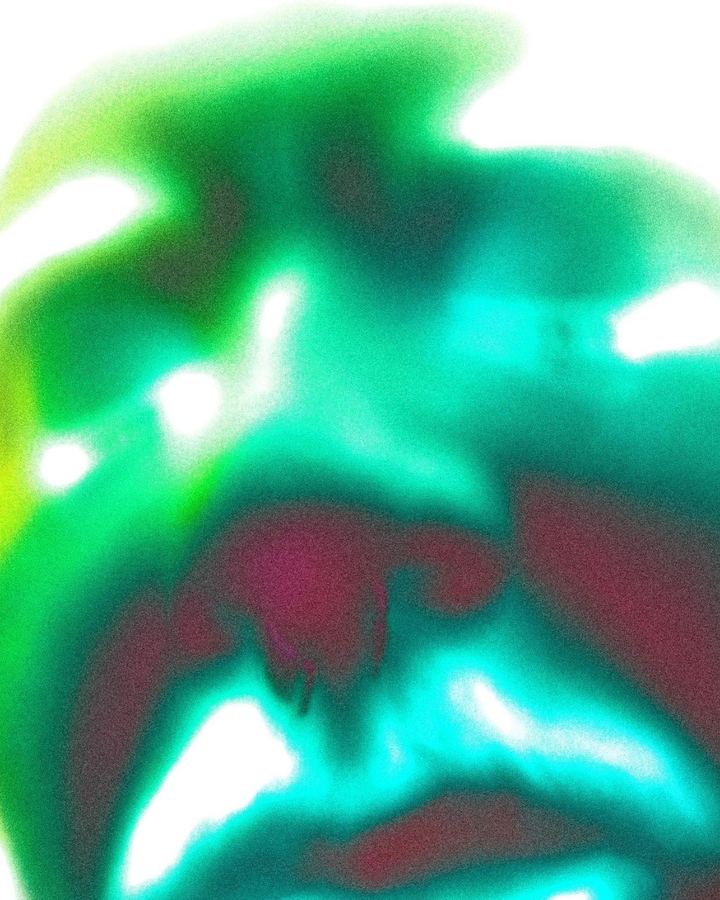 An abstract blur of green, teal and magenta light.