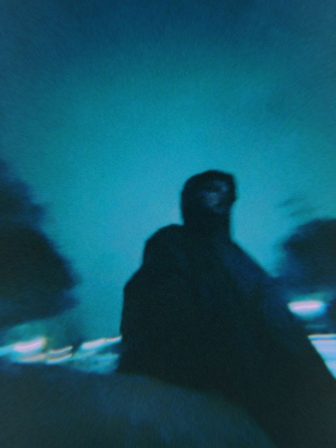 A blurred dark silhouette against a teal sky.