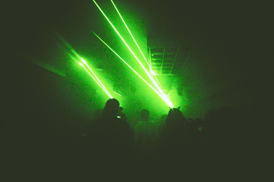 Green laser beams cutting through haze above a crowd.