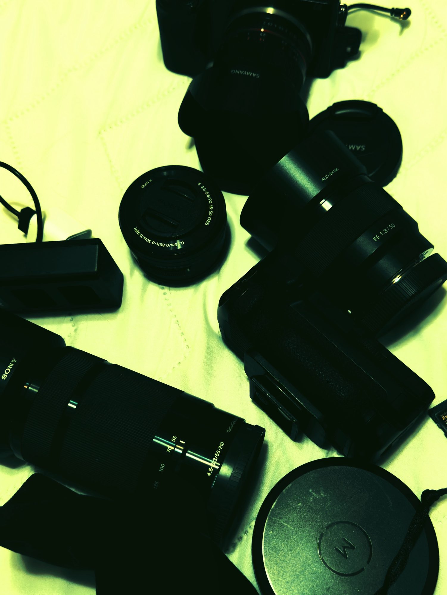 Cameras and lenses scattered across a pale green sheet